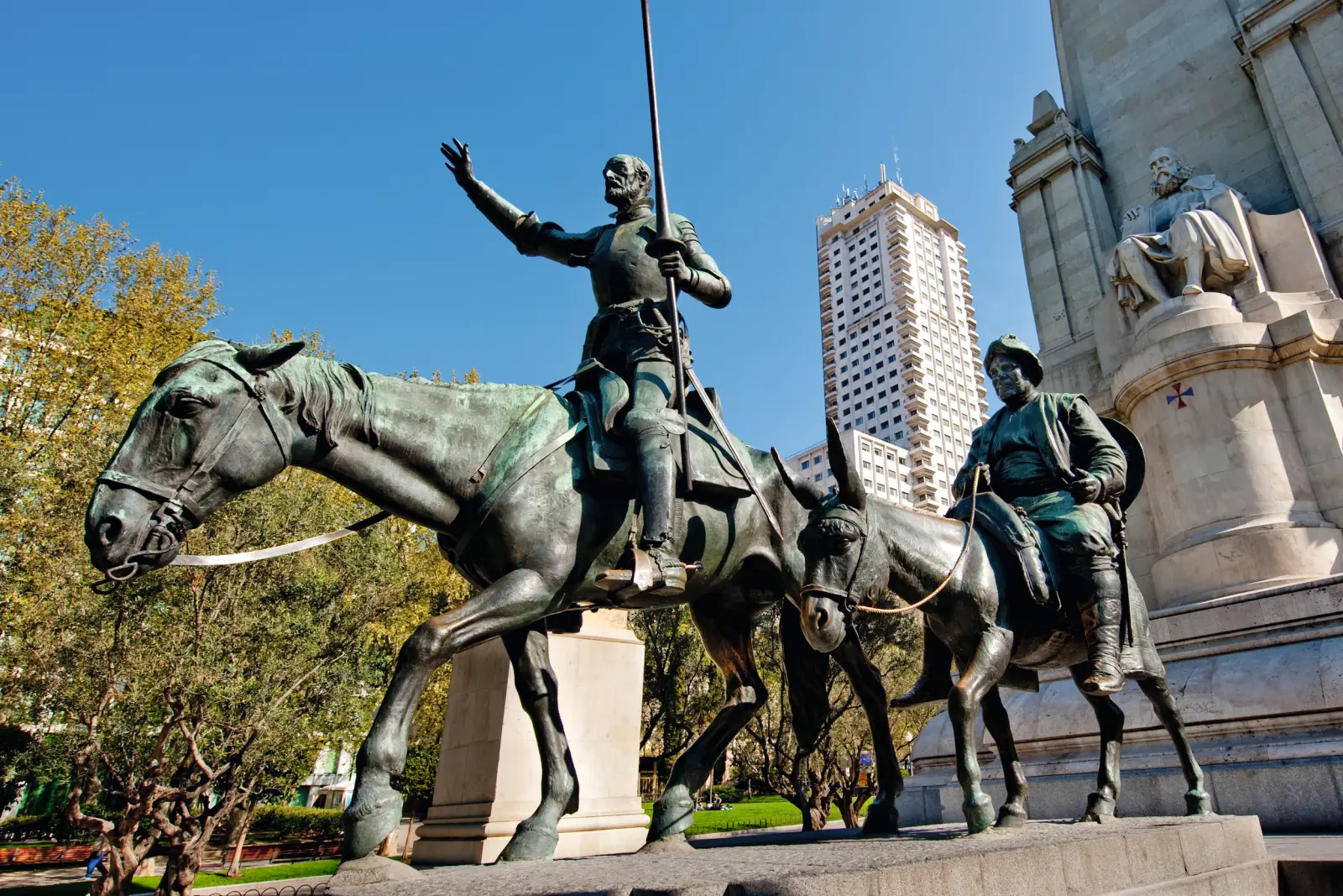 Bronze statue of two horsemen in a city park.