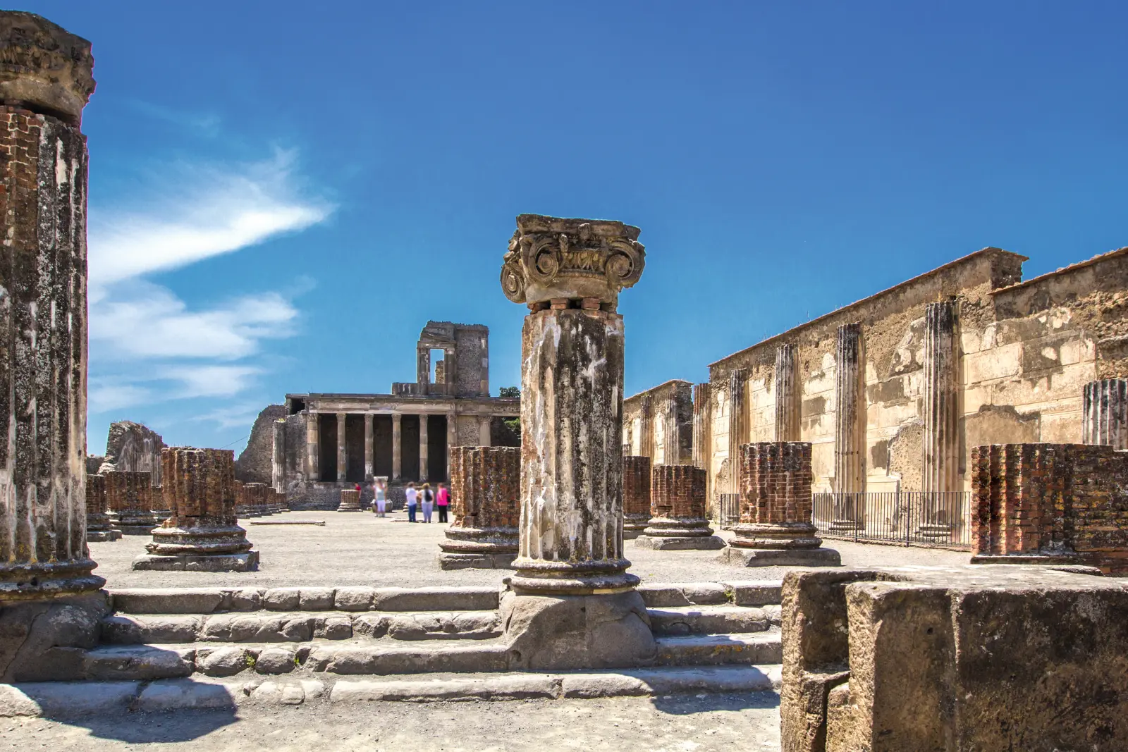 Ruins of an ancient Roman city with remains of columns and a blue sky.