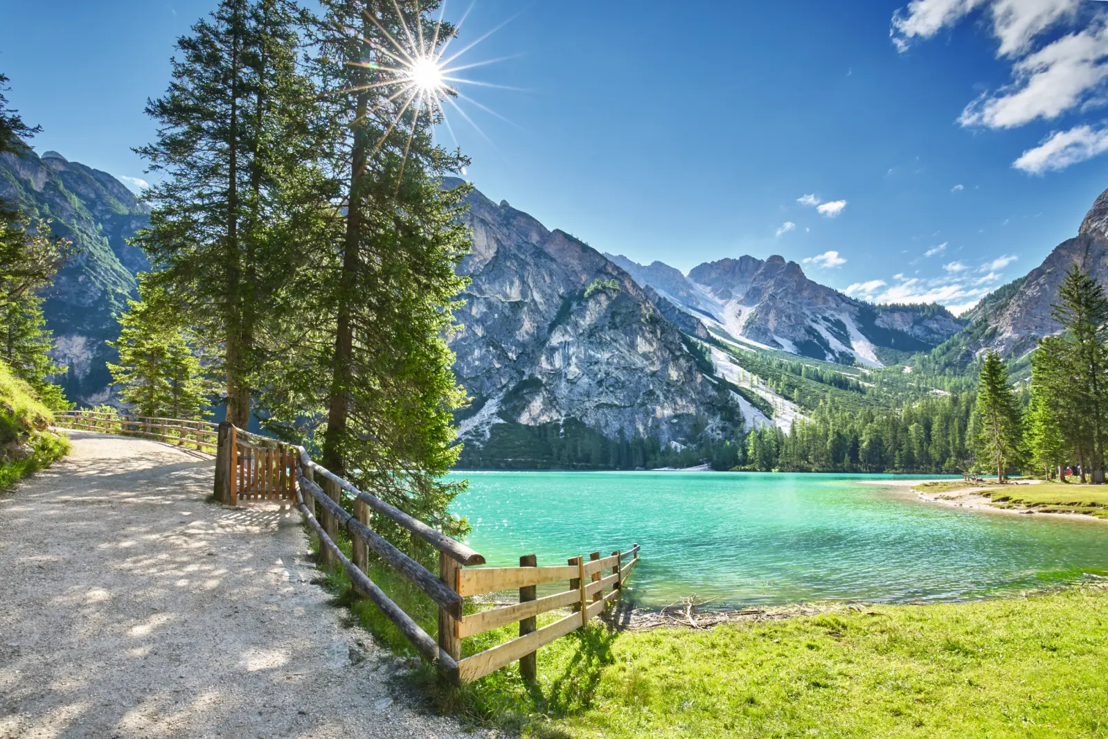 Ein Bergsee mit türkisfarbenem Wasser, umgeben von Bergen und Bäumen.