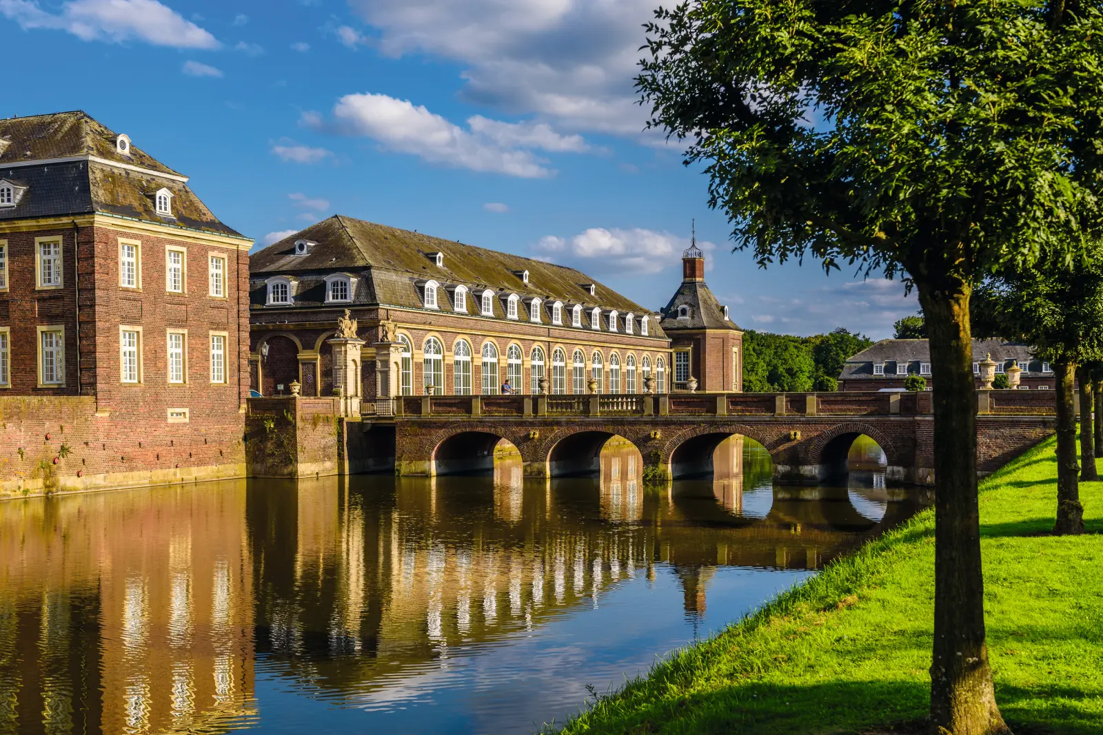 Historisches Schloss mit Wassergraben bei blauem Himmel.