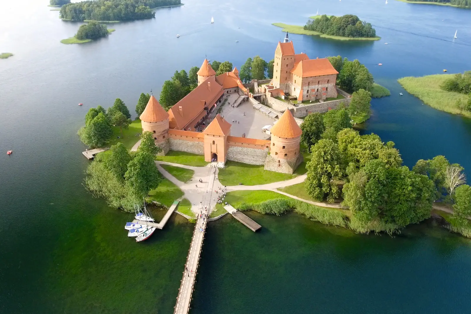 Luftaufnahme einer Burg auf einer Insel inmitten eines Sees mit Wäldern.