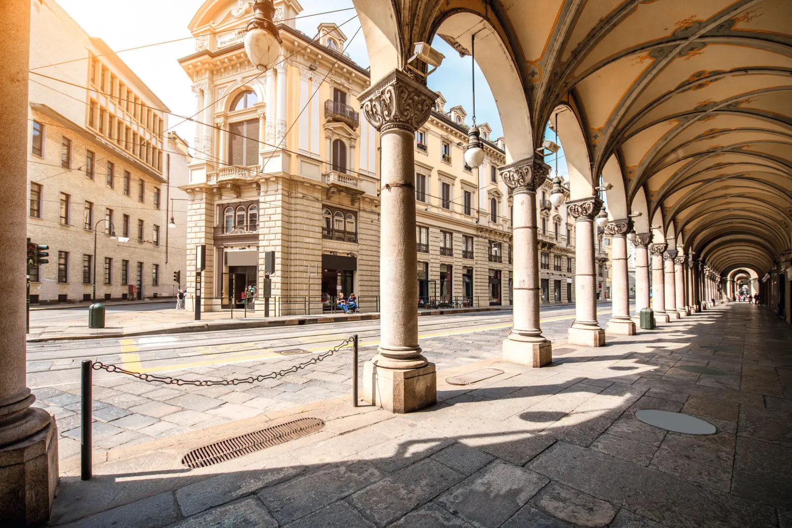 Arcades à colonnes dans une ville européenne ensoleillée.