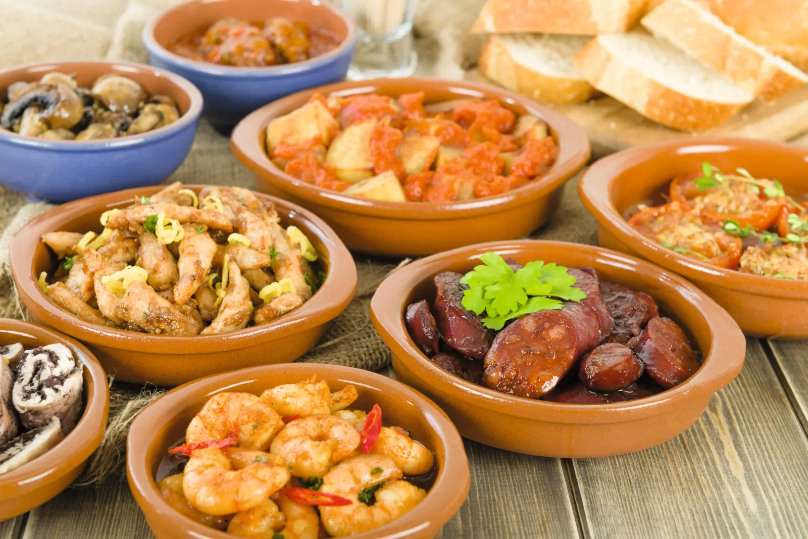 Diversi piatti di tapas in ciotole su un tavolo di legno.