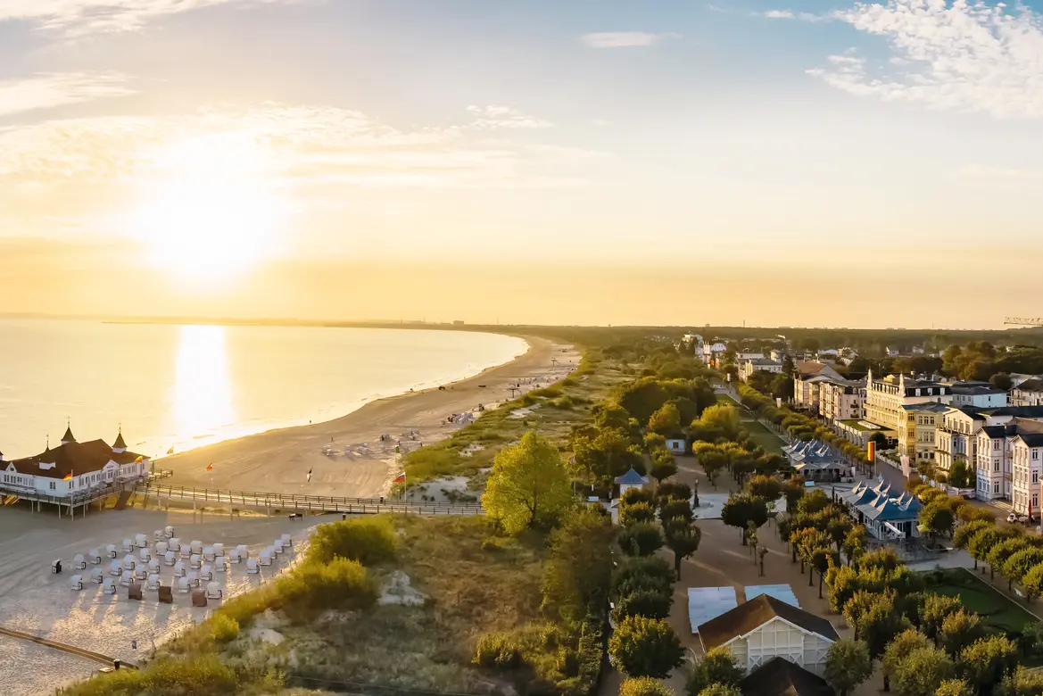 Sunset over a beach with a pier and a coastal town