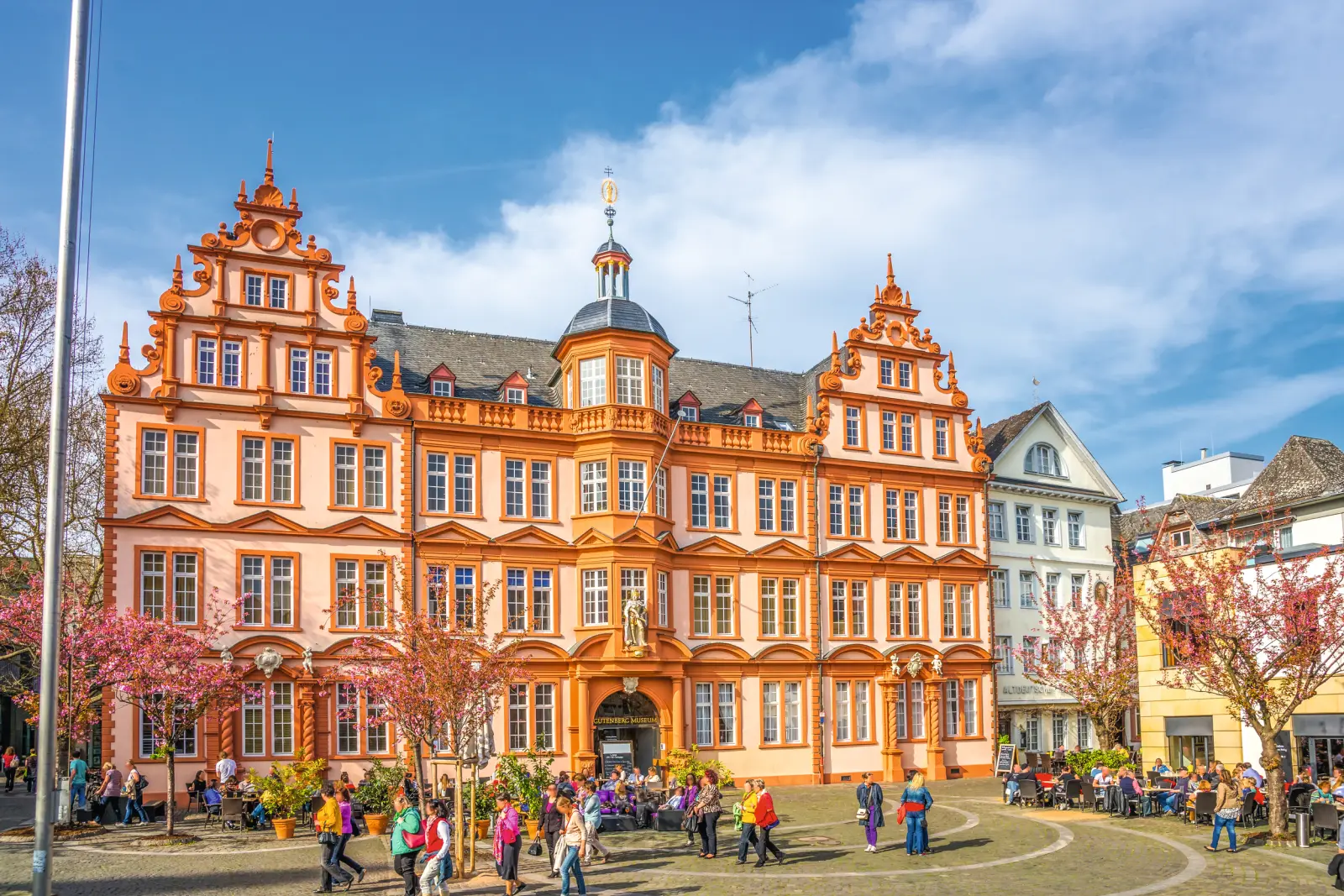 Historic building with an orange façade and people in the foreground.