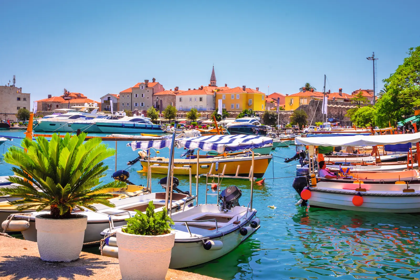 Boats in the harbour in front of a colourful old town in sunny weather.