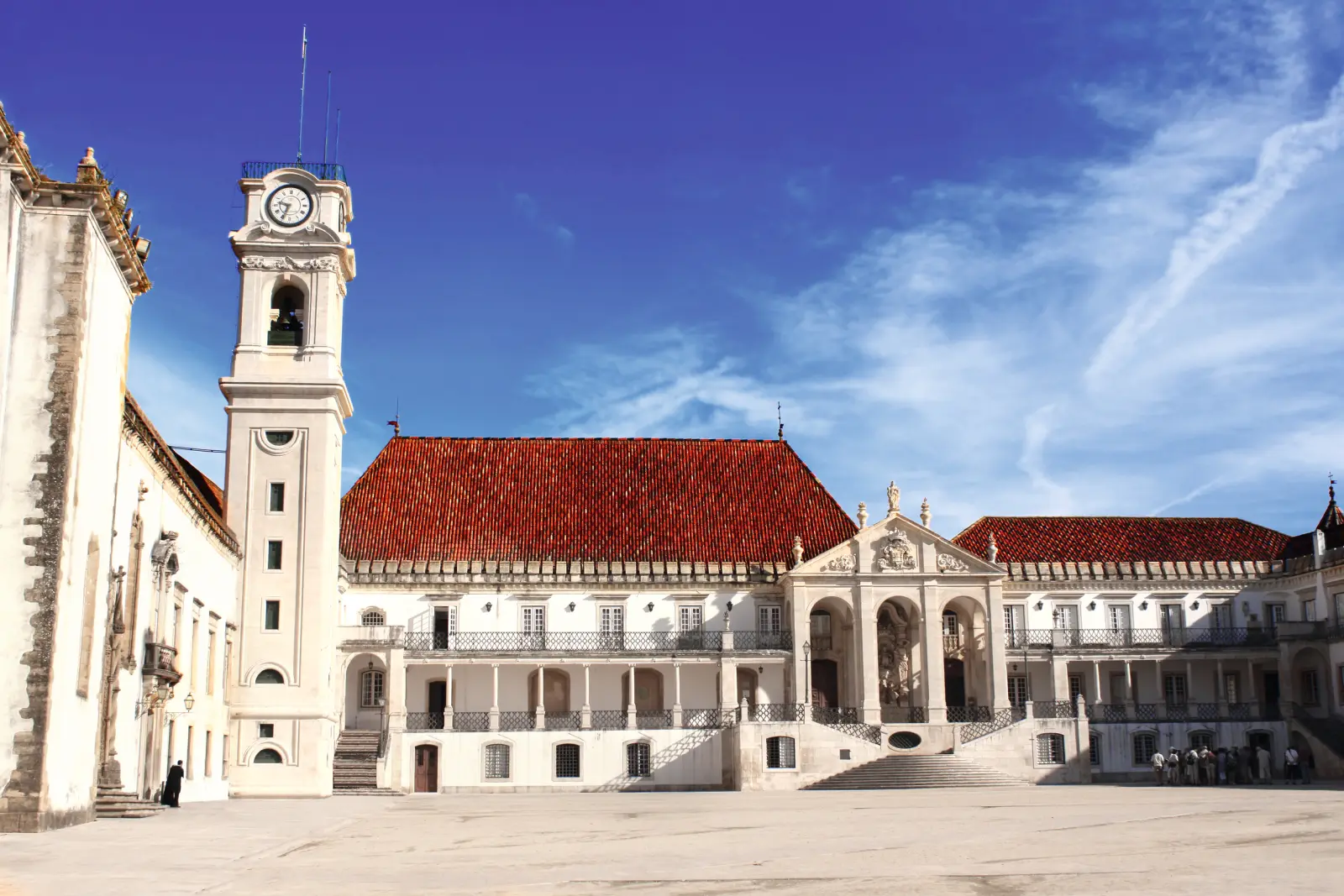 Historic building with a clock tower and red roof under a blue sky.