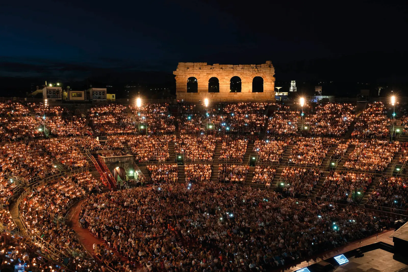 Illuminated Arena in Verona at night with a large audience.