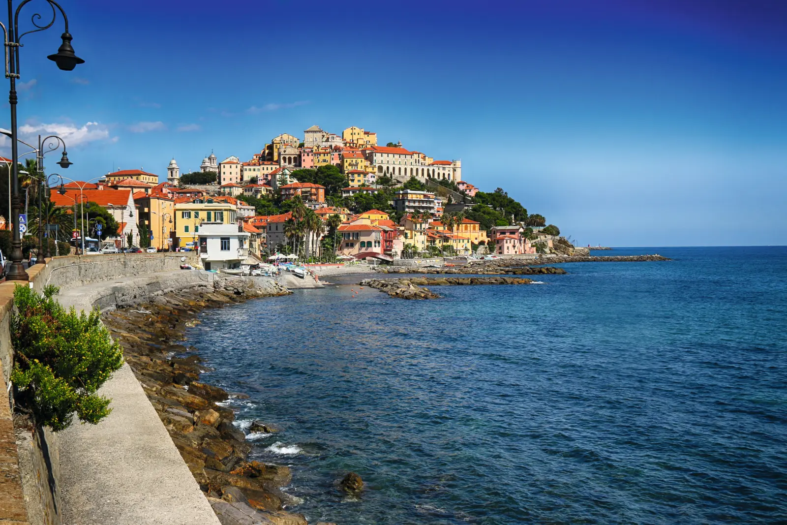 Colorata cittadina costiera in una giornata di sole con vista sulle montagne e sul mare.