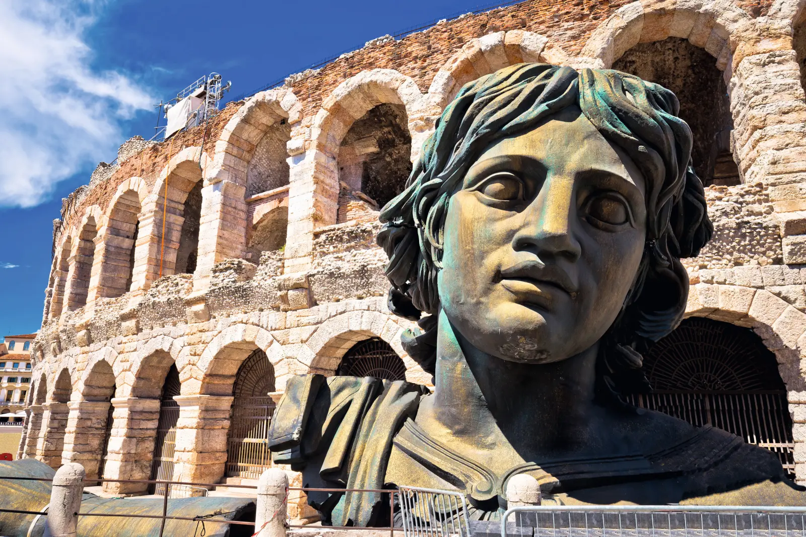 Büste vor einem antiken Amphitheater aus Stein mit Bögen.