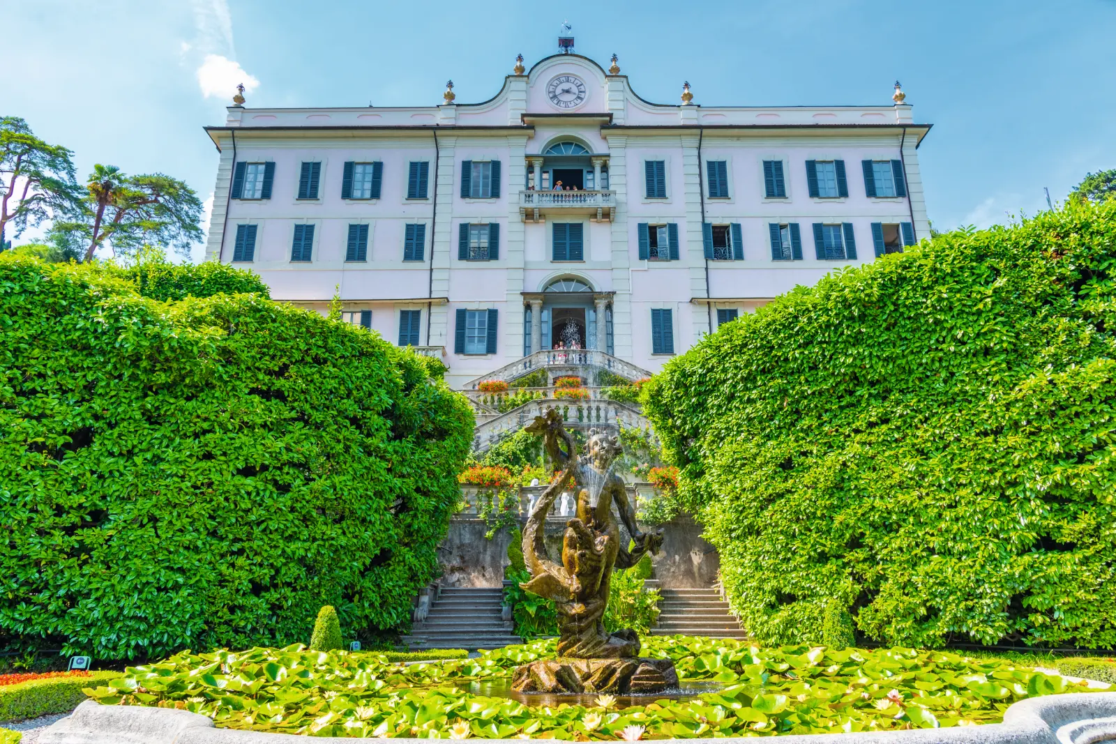 Bâtiment historique avec jardin et fontaine au premier plan.