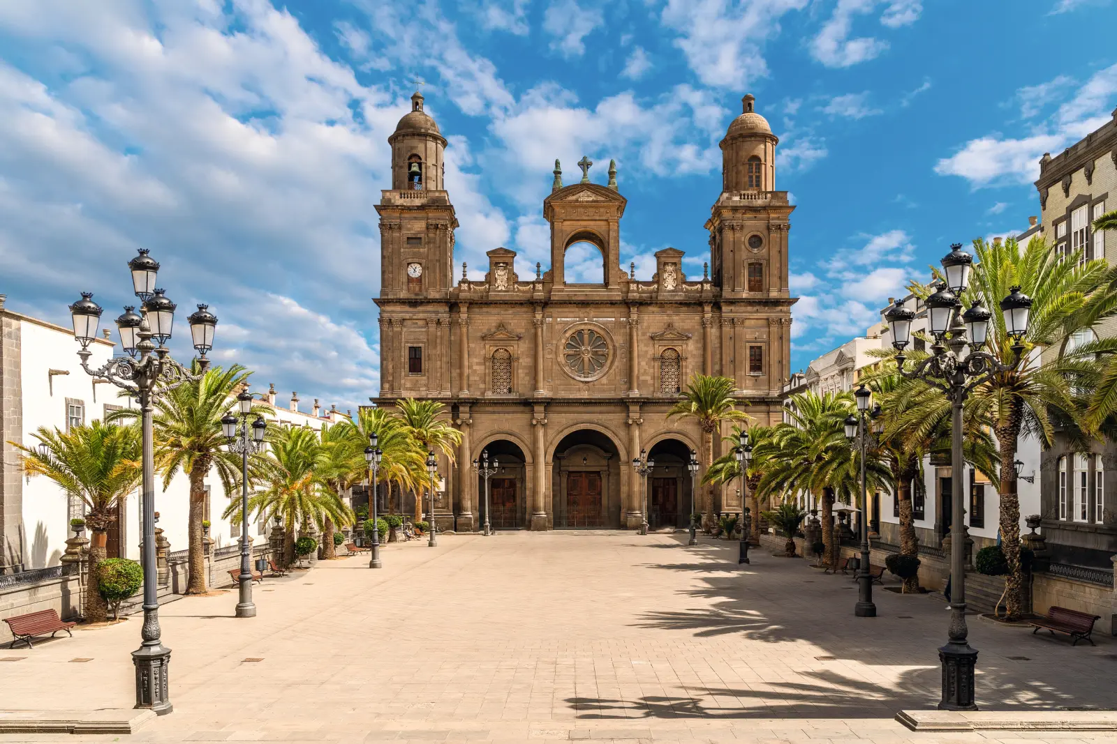 Cattedrale con torri e palme in una piazza soleggiata.