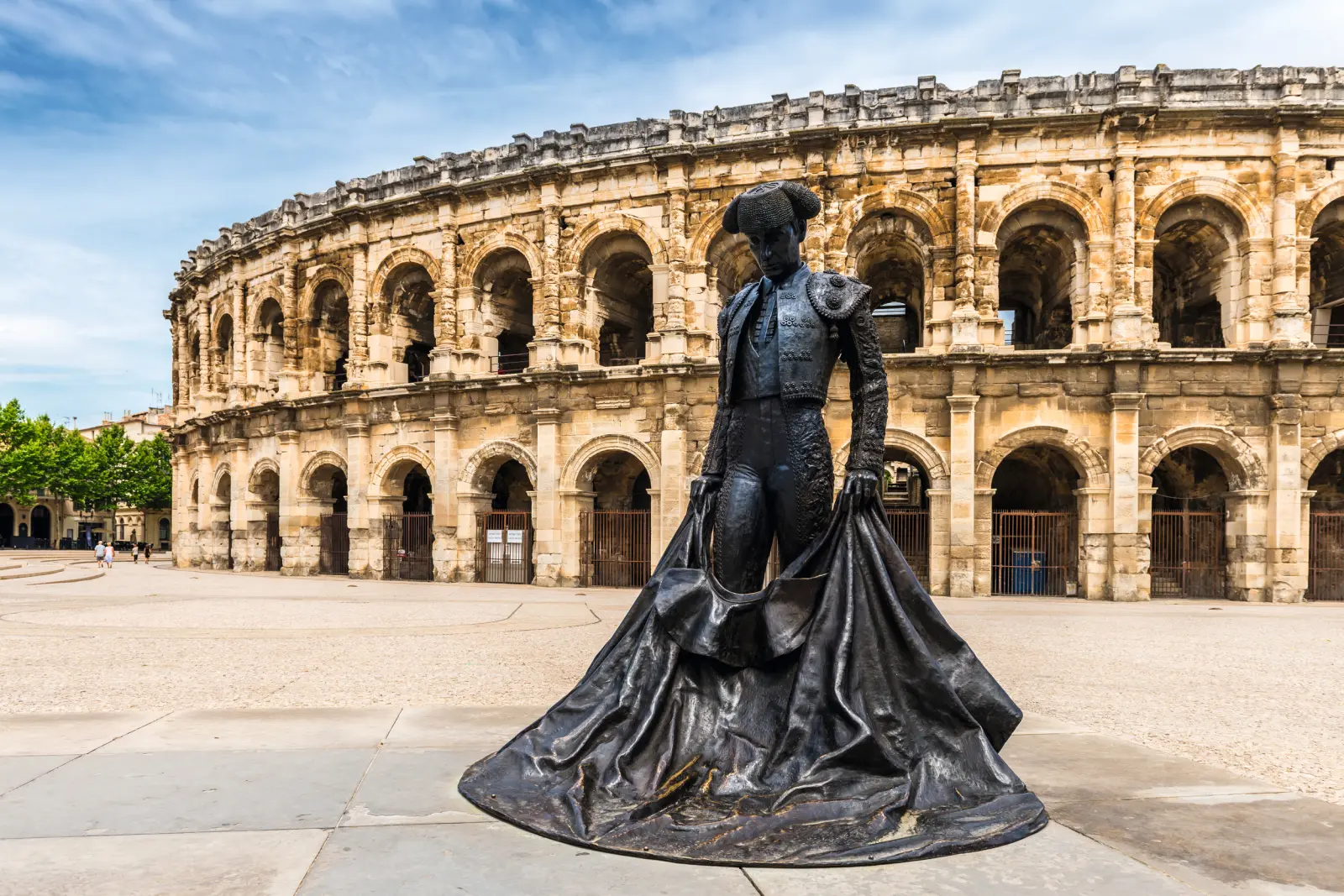 Stierkämpferstatue vor antikem römischen Amphitheater.
