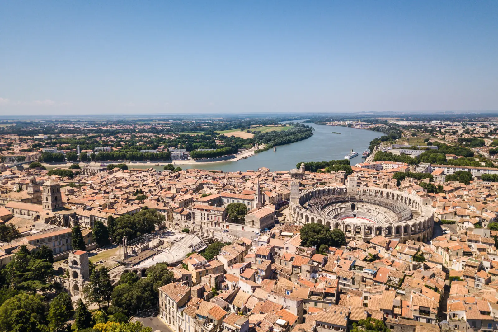 Aerial view of an ancient arena in a town with a river in the background.