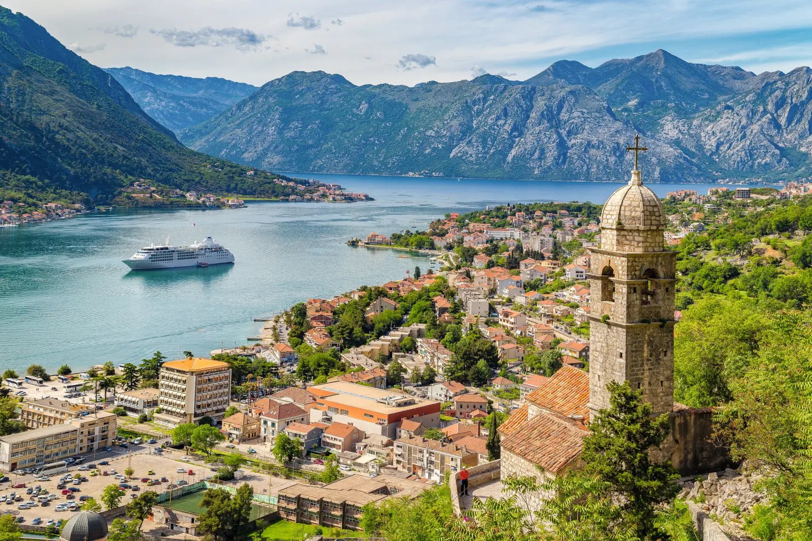 Ville côtière de Kotor avec un bateau de croisière et des montagnes à l’arrière-plan.