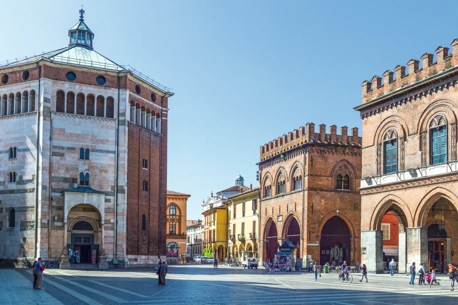 Piazza storica con antichi edifici in mattoni sotto un cielo azzurro e limpido.