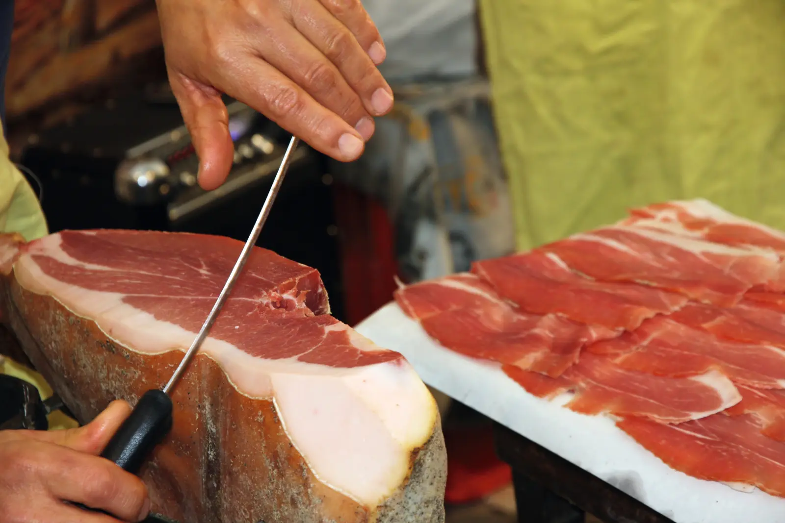 Une personne coupe du jambon en fines tranches.