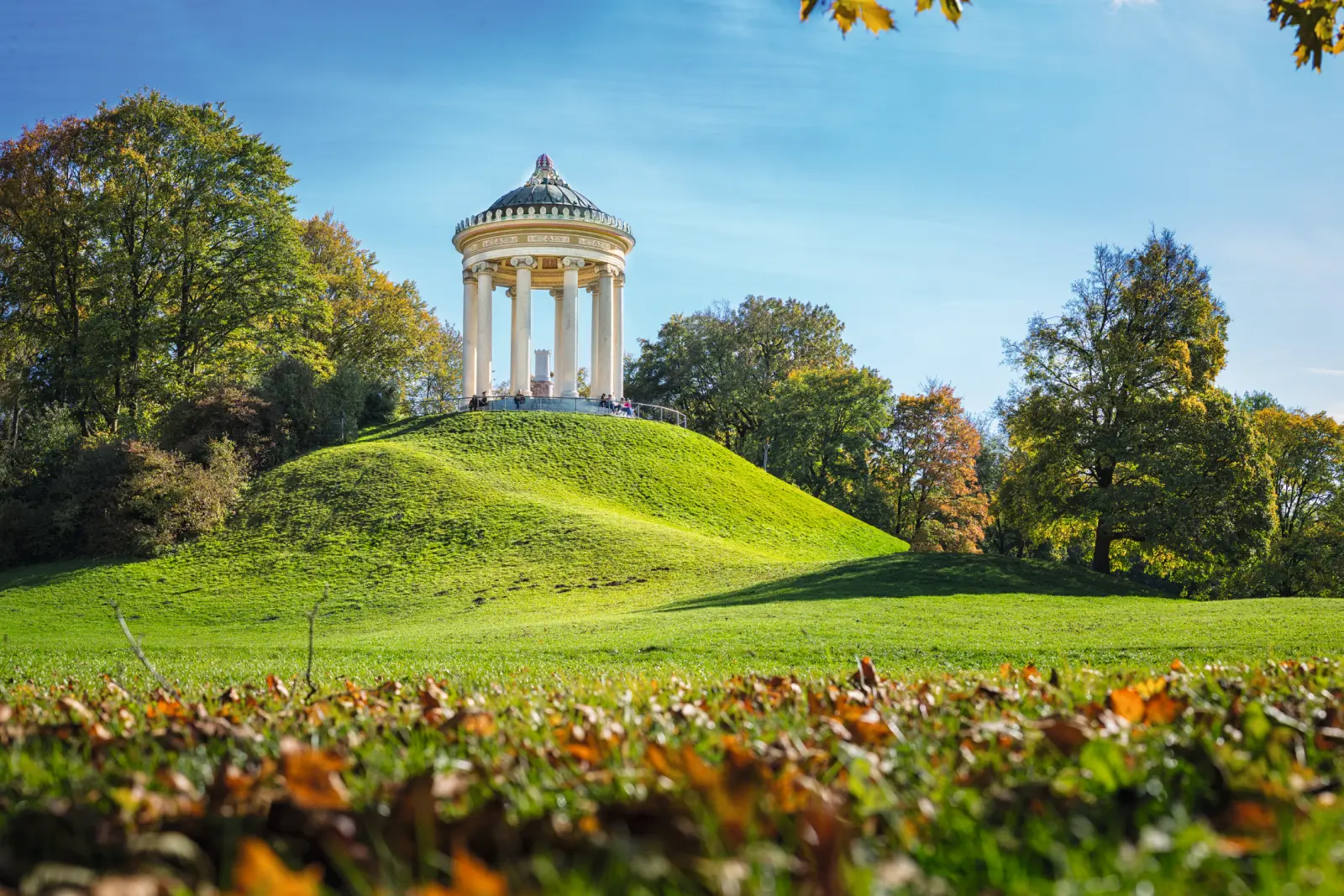 Pavillon dans le Jardin anglais de Munich, entouré de verdure et d’arbres aux couleurs d’automne.