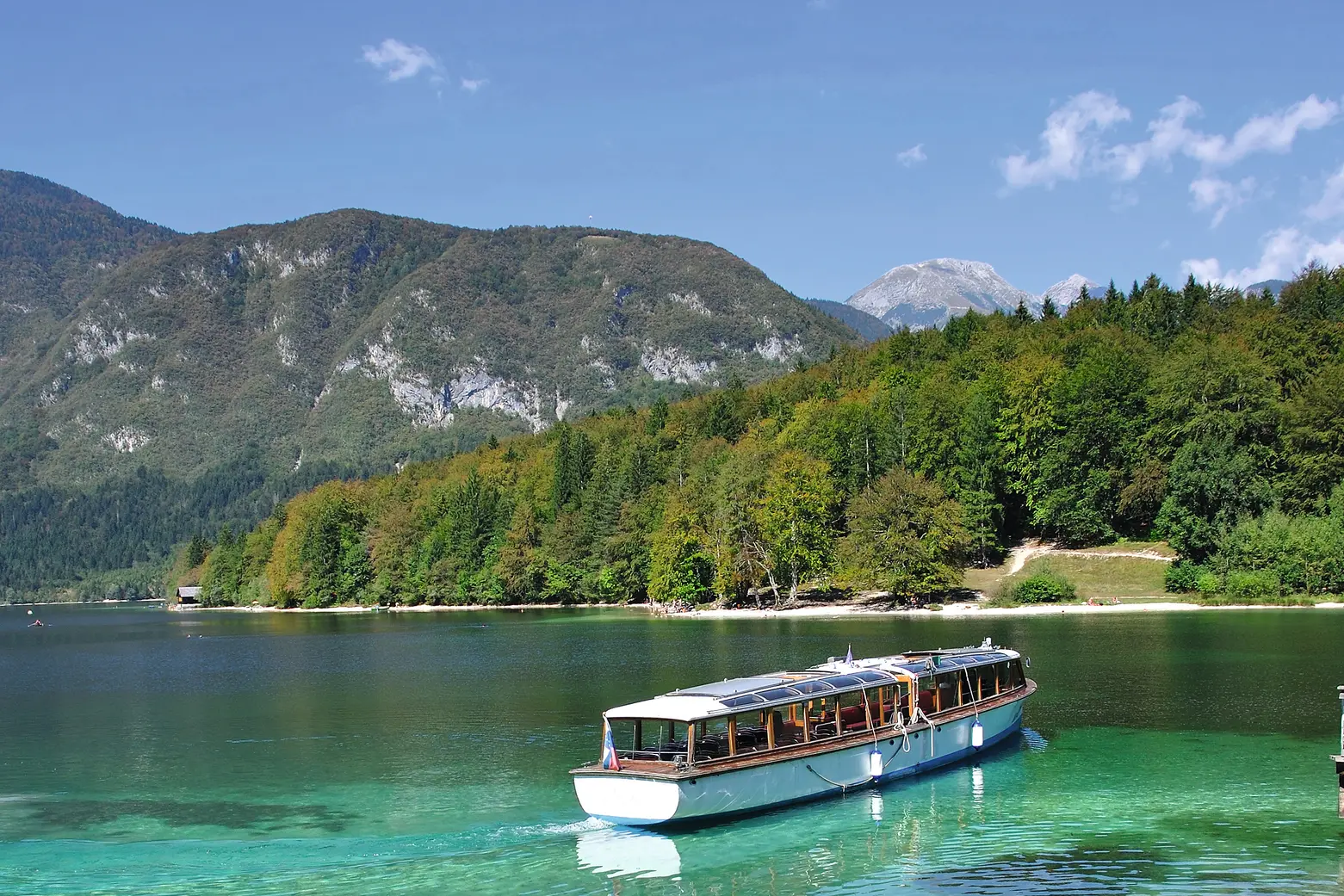 Boot auf einem klaren Bergsee mit Wald und Bergen im Hintergrund