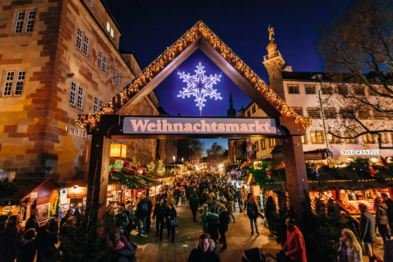 Portail d’entrée du marché de Noël de Stuttgart de nuit, devant des bâtiments historiques.