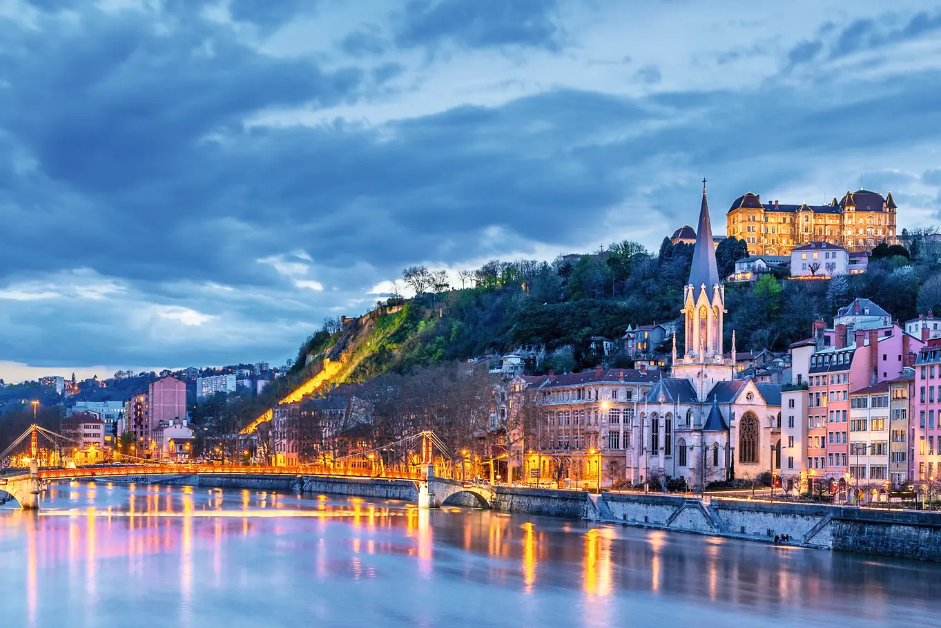 View of Lyon at dusk, with illuminated buildings along the river.