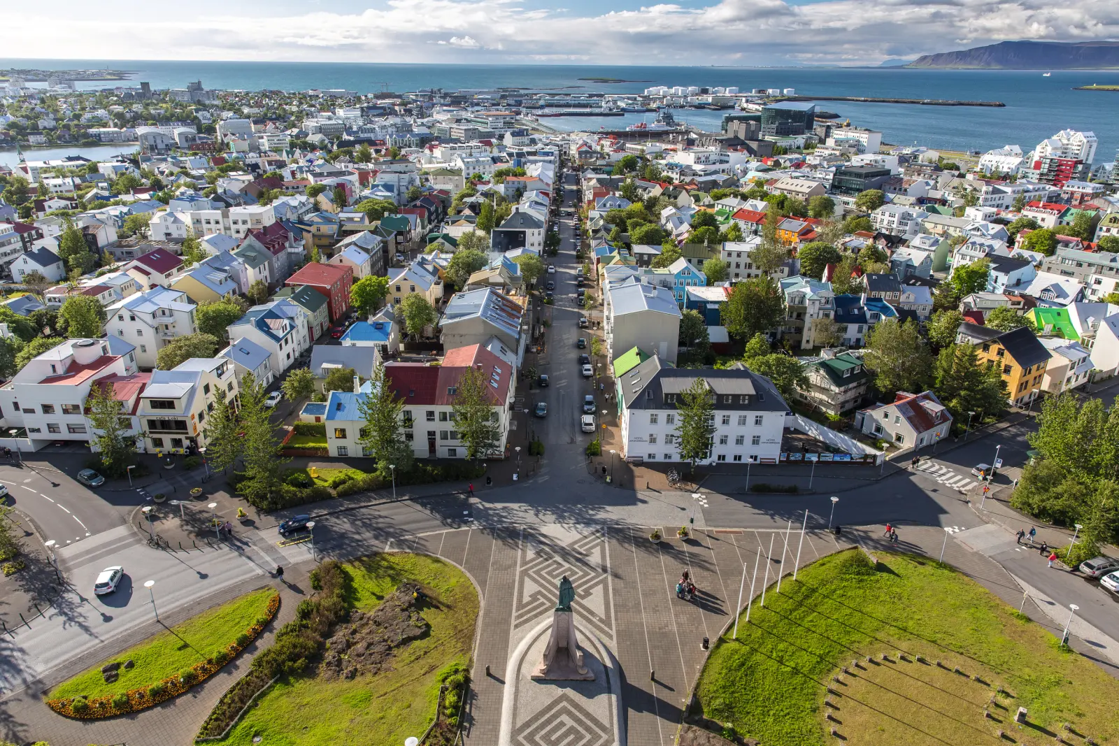 Vue sur la ville côtière de Reykjavik avec ses maisons colorées, ses rues et un port à l’arrière-plan.