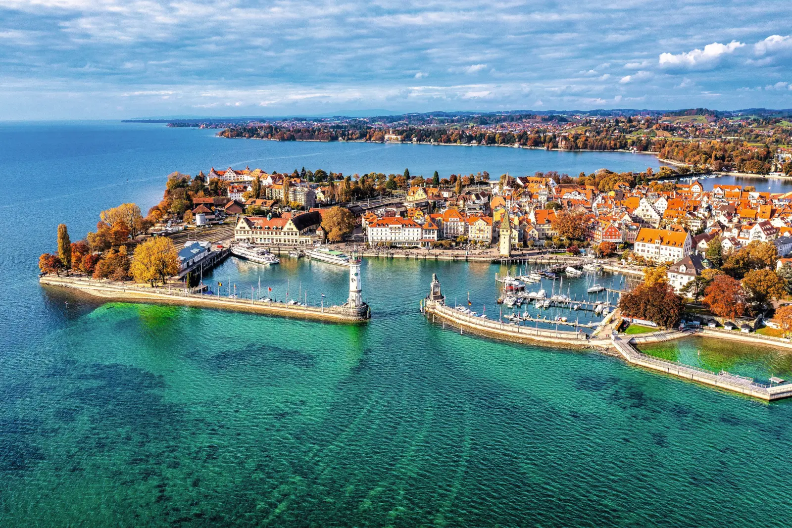 Veduta aerea di una città portuale con laghi e alberi autunnali.