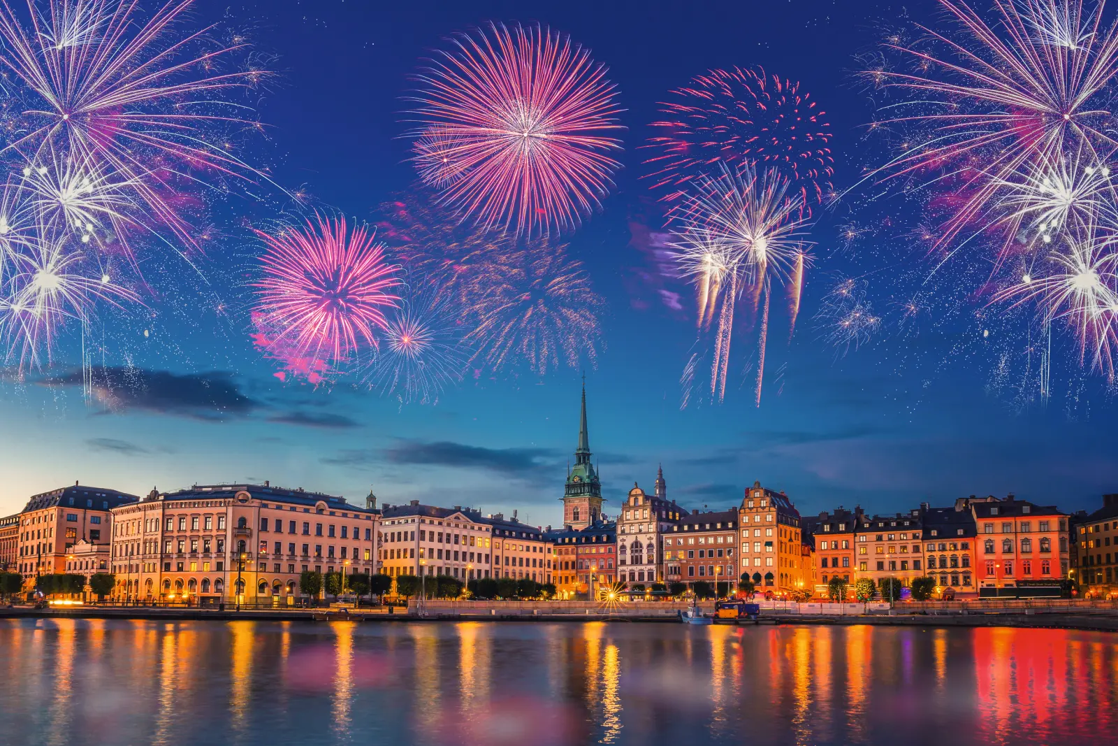 Feu d’artifice au-dessus d’une ville avec des bâtiments illuminés de nuit.
