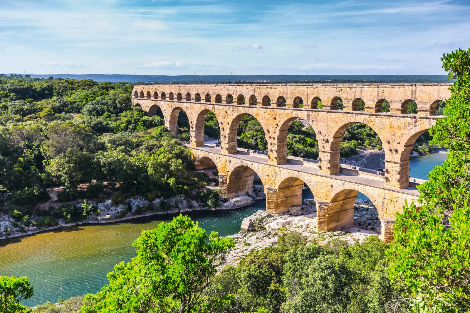 Pont du Gard, römischer Aquädukt über einen Fluss in bewaldeter Landschaft.