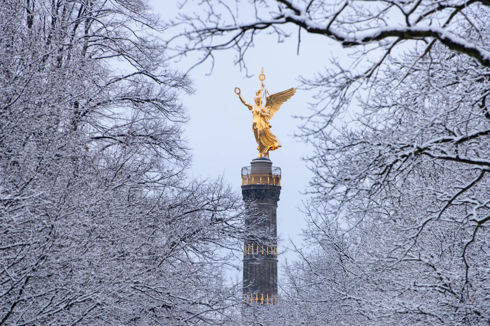 La colonne de la Victoire à Berlin, entourée d’arbres enneigés en hiver.