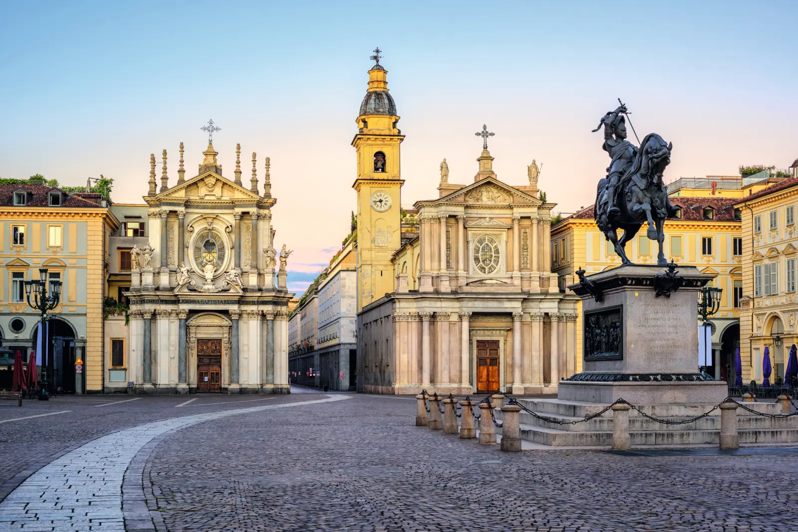 Place historique avec une église et une statue équestre au coucher du soleil.
