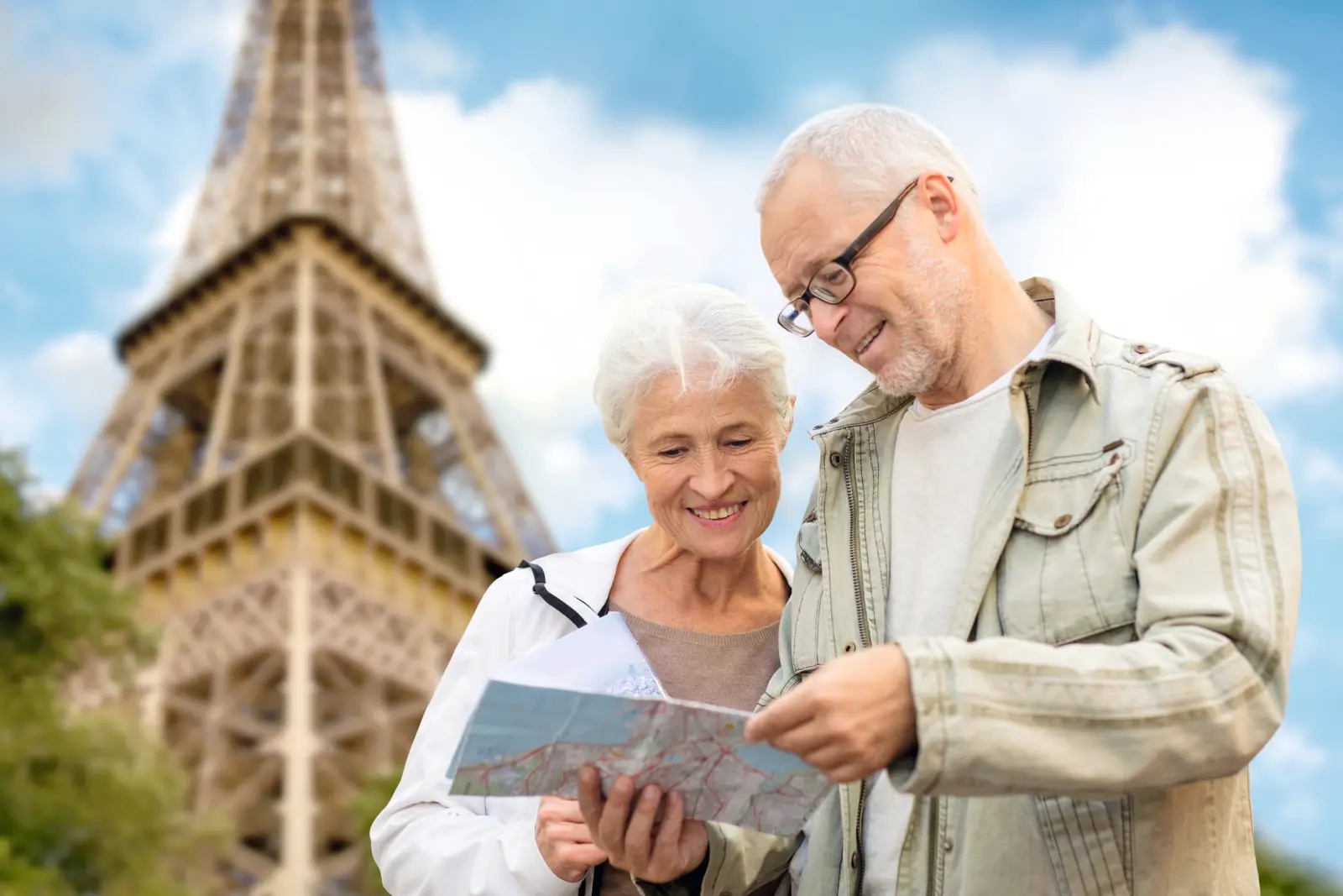 Couple âgé regardant une carte devant la tour Eiffel à Paris.