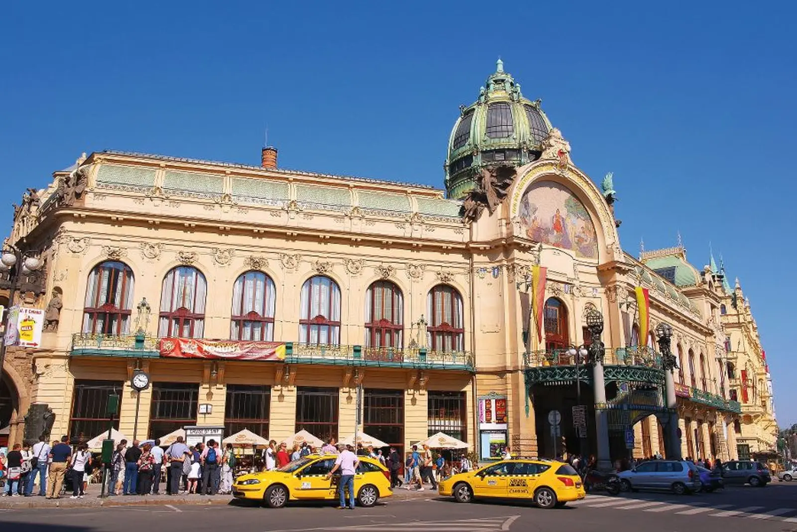 Historisches Gebäude mit Kuppel in Prag, Menschen und Taxis davor.