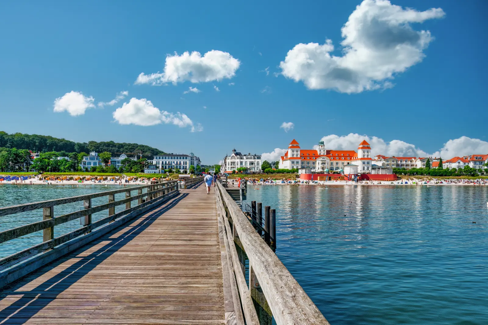 Passerella in legno sul mare con vista su edifici e cielo nuvoloso