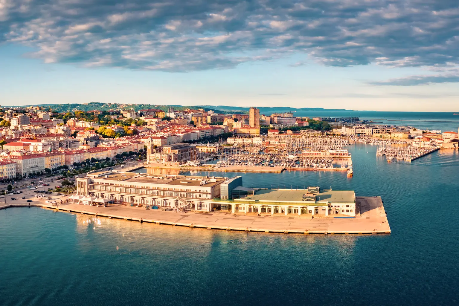 Ville côtière avec port et bâtiments sous un ciel bleu.