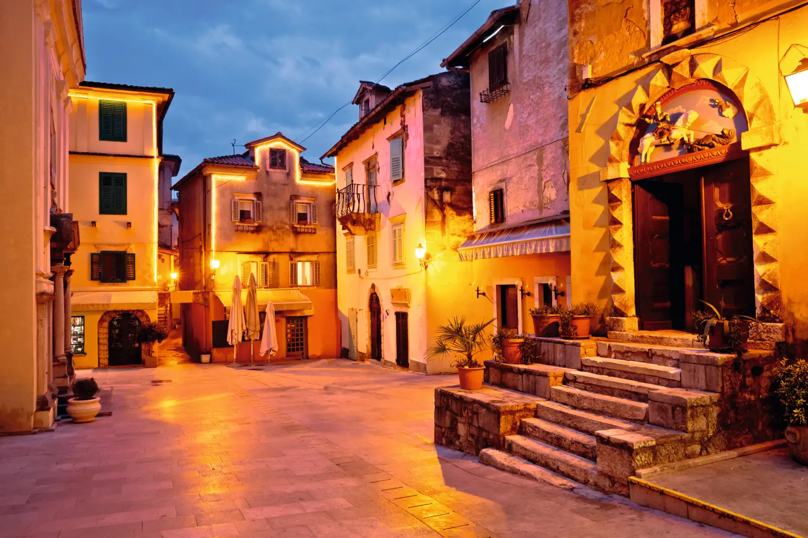 Pittoresca piazza con edifici storici al crepuscolo, illuminata da una luce calda.