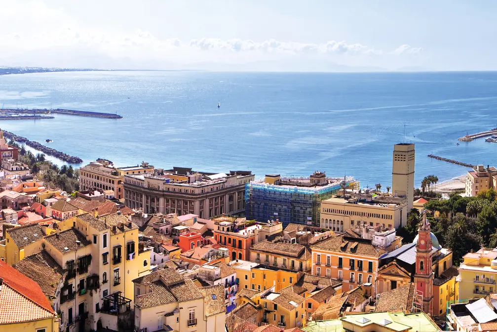 View of a town with coastline and mountains under a clear sky.