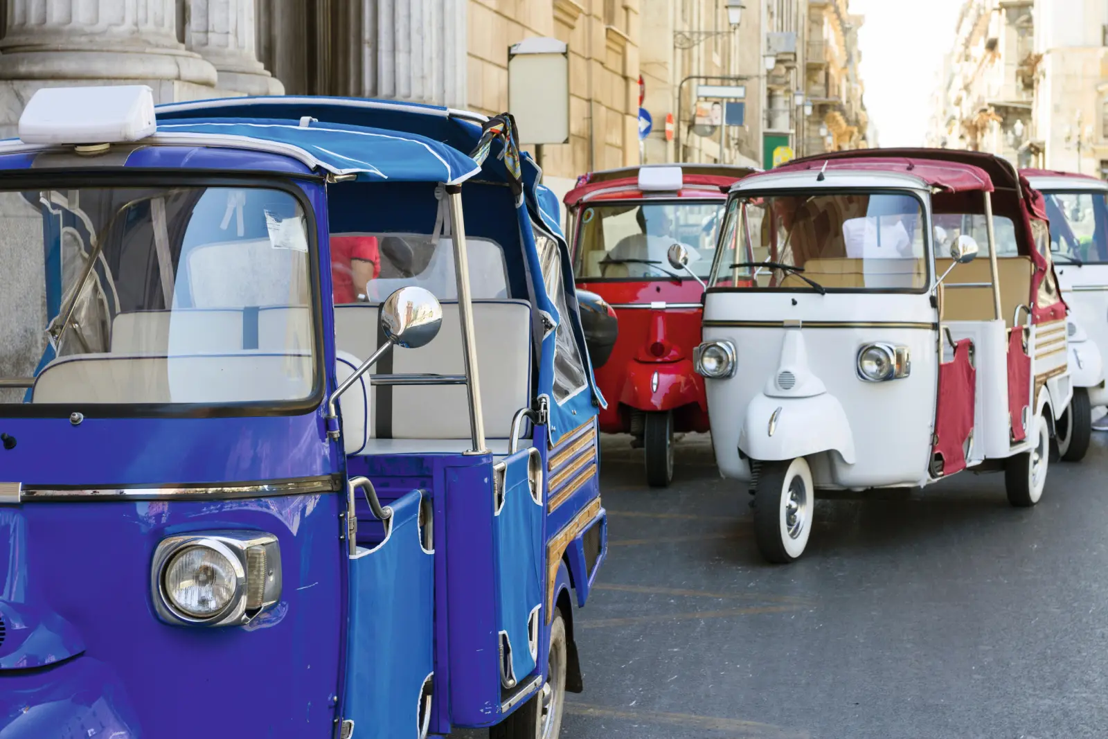 Tre variopinti tuk-tuk percorrono una strada cittadina.