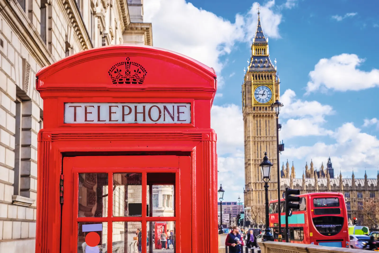 Cabine téléphonique rouge et Big Ben à Londres sous un ciel bleu.