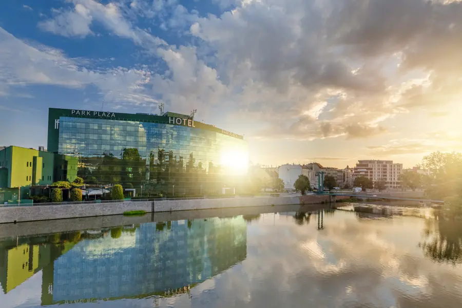 Hotel building by the river at sunset, reflected in the water.