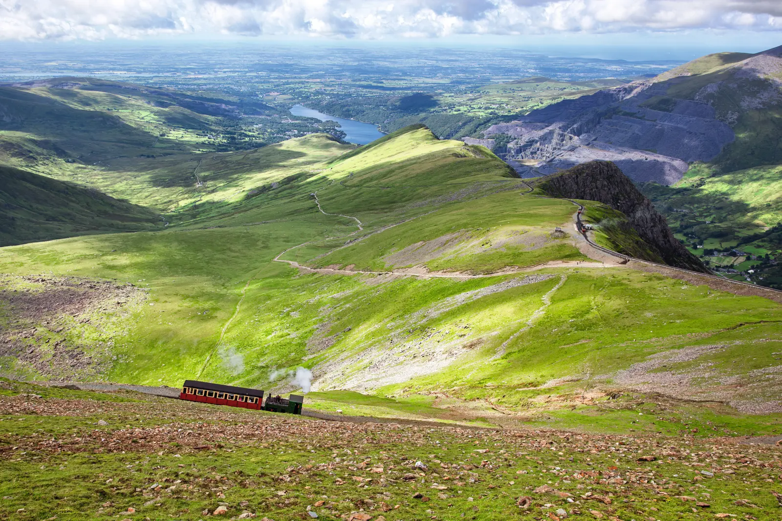 Treno su una linea di montagna con verdi colline sullo sfondo.
