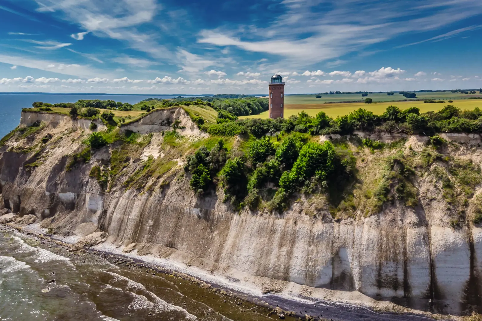 Paysage de falaises avec phare et ciel nuageux au bord de la mer.