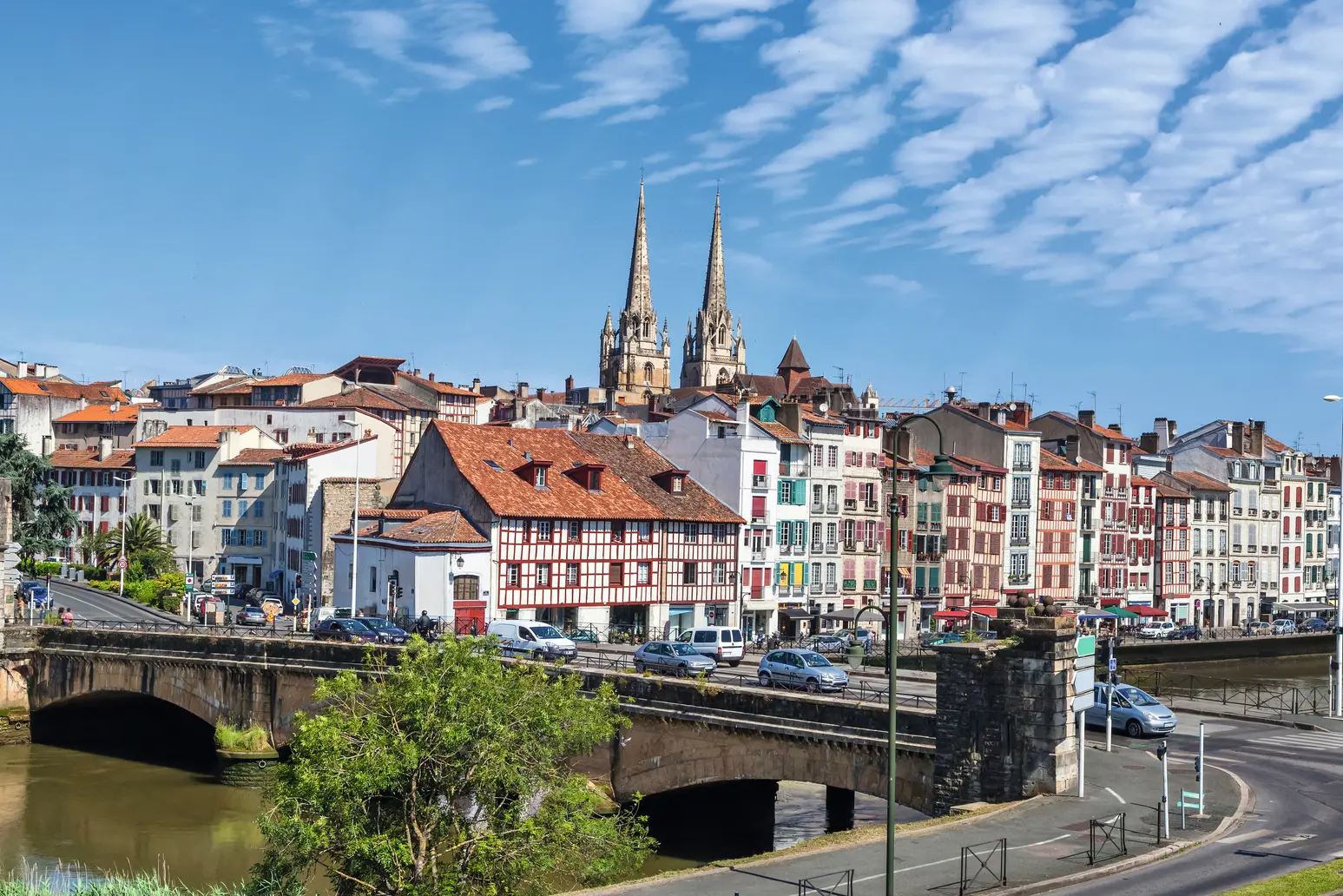 Blick auf Stadt mit Fluss, Brücke und Kirchen im Hintergrund.