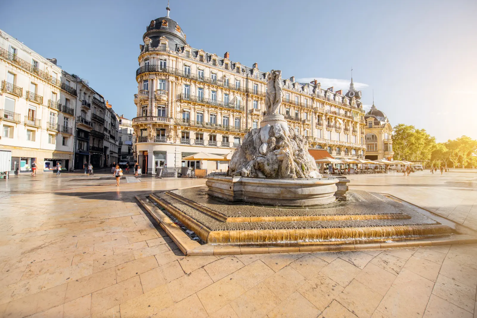 Platz in Montpellier, Frankreich mit historischem Gebäude und Brunnen bei sonnigem Wetter.