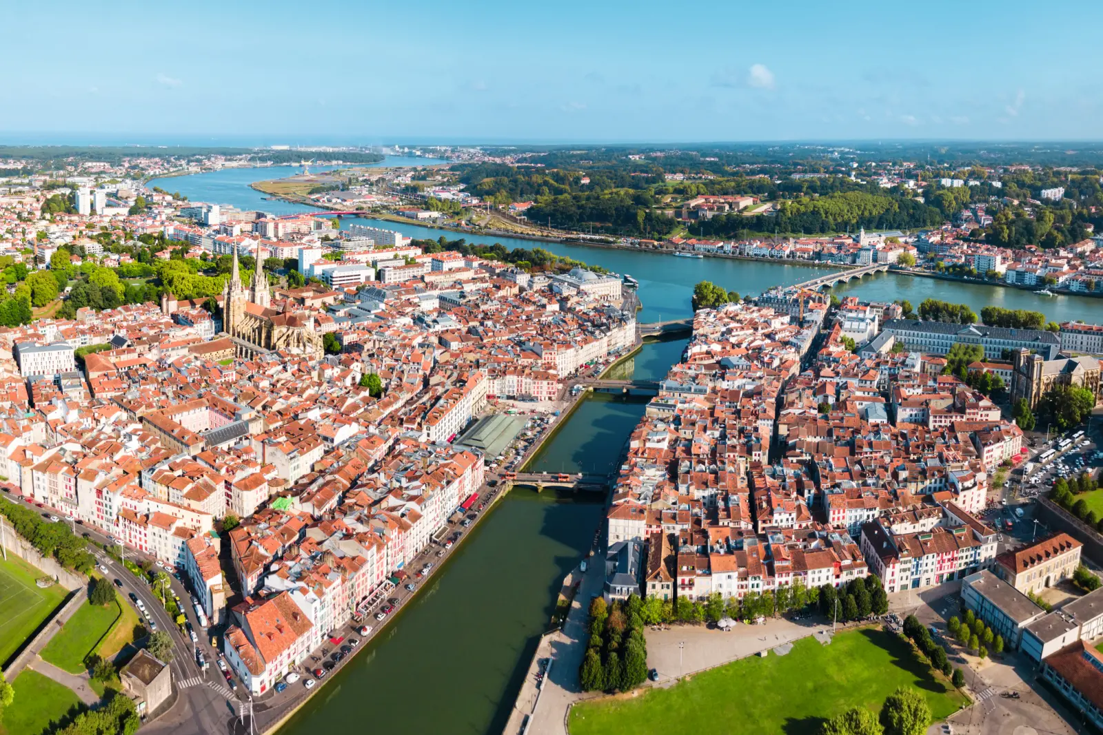 Luftaufnahme einer Stadt mit Fluss und Brücken im Sonnenschein.