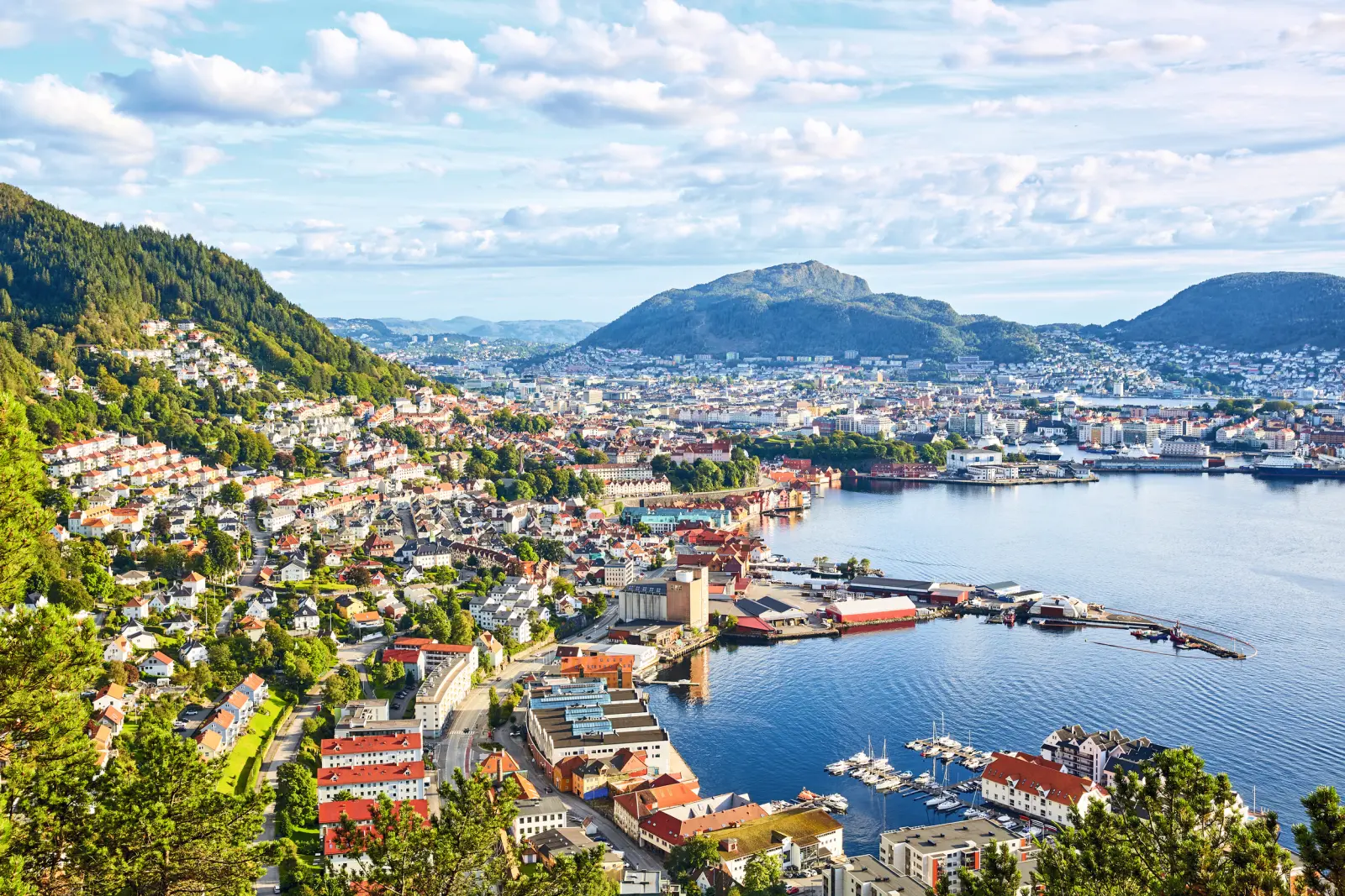 View of the city of Bergen in Norway with mountains and harbour under a blue sky.