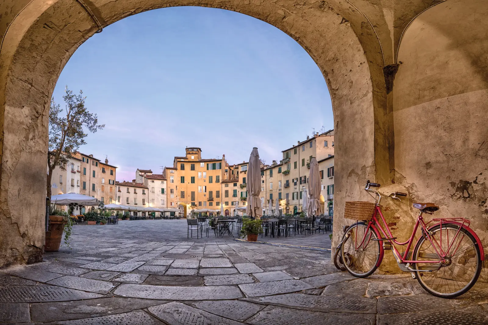 Red bicycle frame in a historic town with a view of arcades, deserted square.