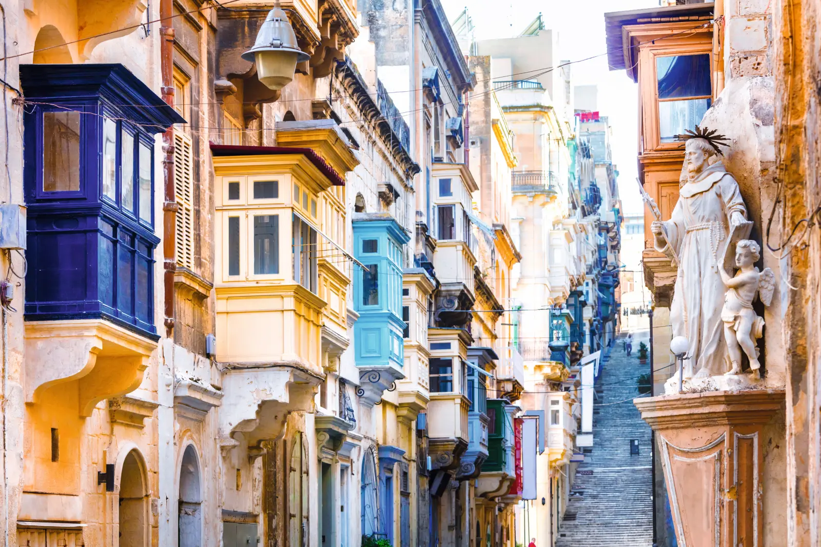 Colourful balconies along a narrow, steep lane in a historic town.