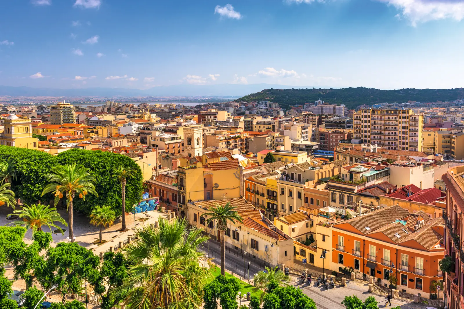 Townscape with colourful houses and green trees under a blue sky.