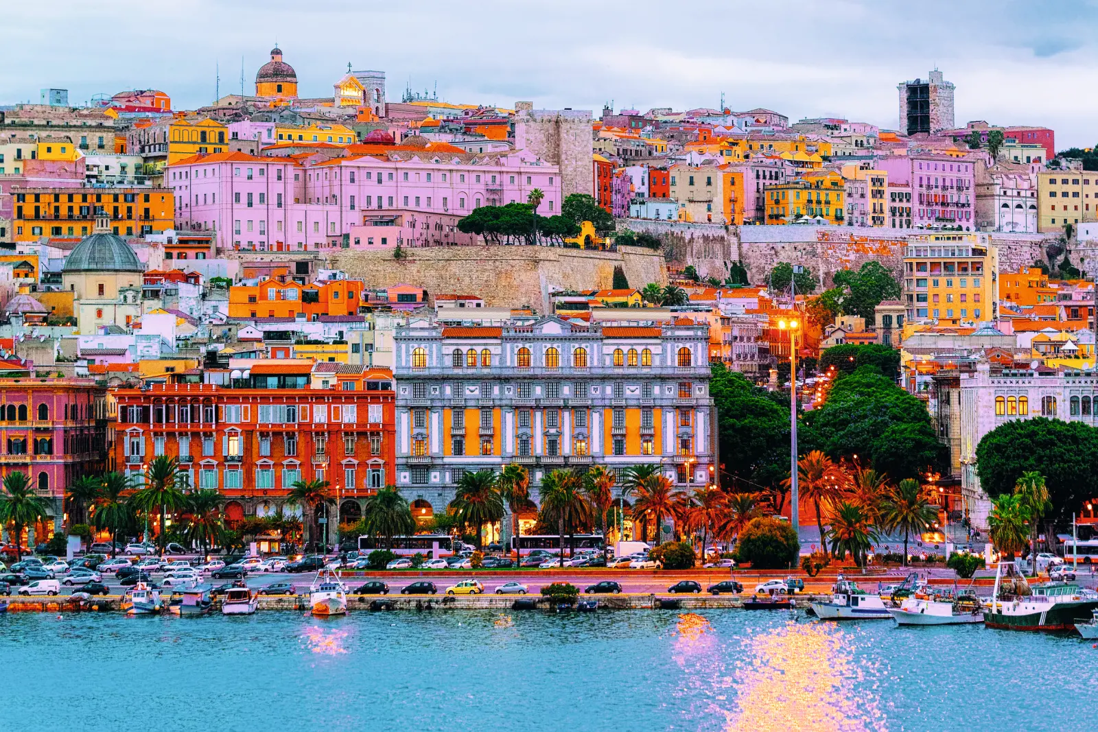Port of Cagliari in Sardinia with historic buildings and boats in the foreground.